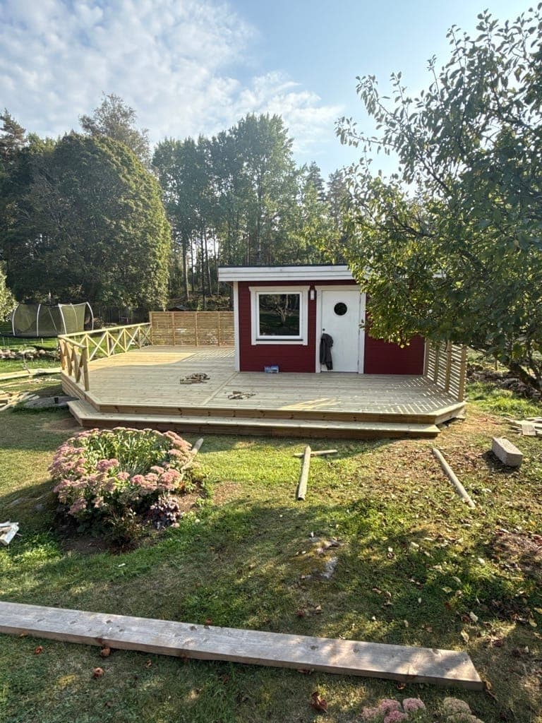 Röd gäststuga med expansivt trädäck