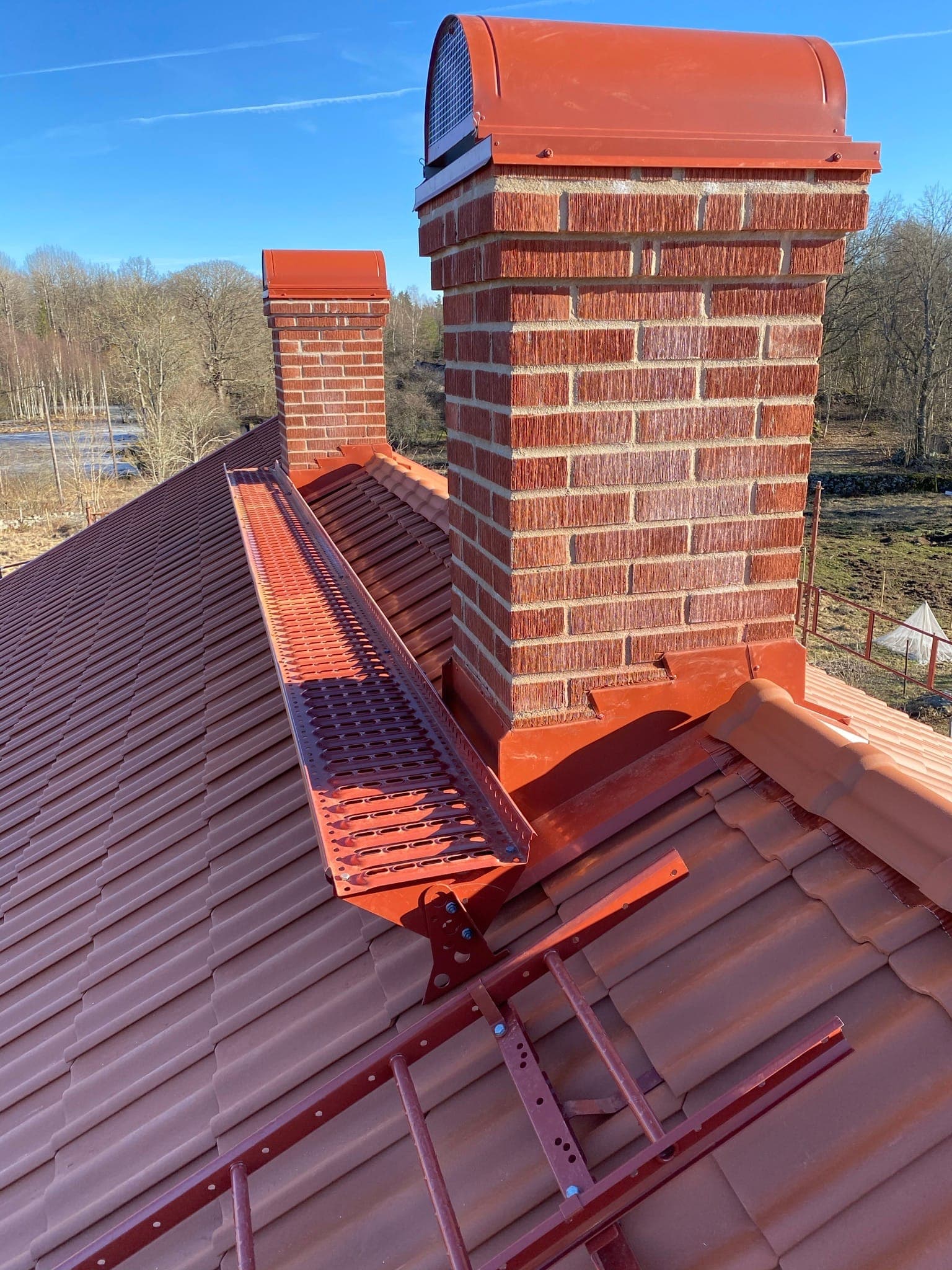 Rött tegeltak med skorstenar och takgångbro