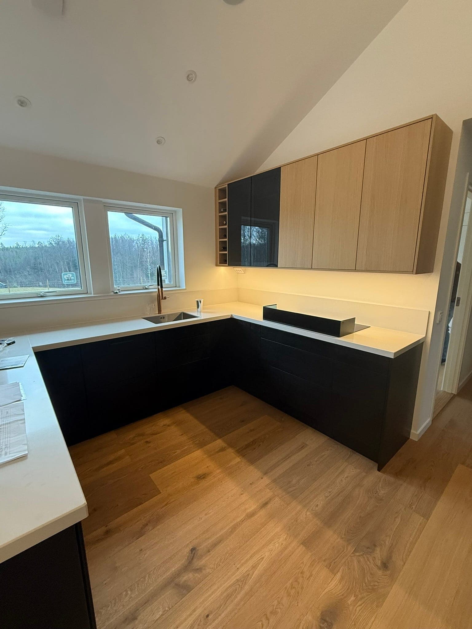 L-format kök med vita bänkskivor och svarta skåp